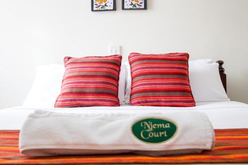 a bed with two pillows and a white blanket at Njema Court Apartment in Nairobi