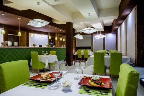 a dining room with white tables and green chairs at Hotel SPA Dr Irena Eris Krynica Zdrój in Krynica Zdrój