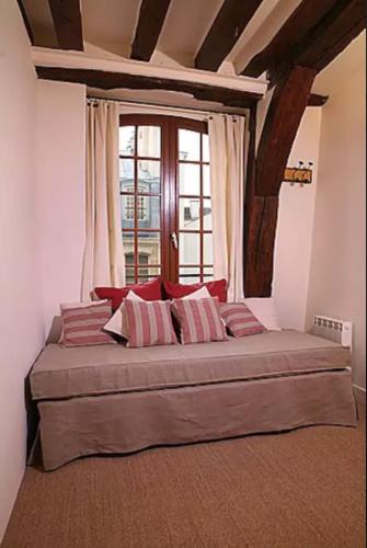 un grand lit dans une chambre avec une fenêtre dans l'établissement Charming Cosy Triplex in Trendy Marais, à Paris