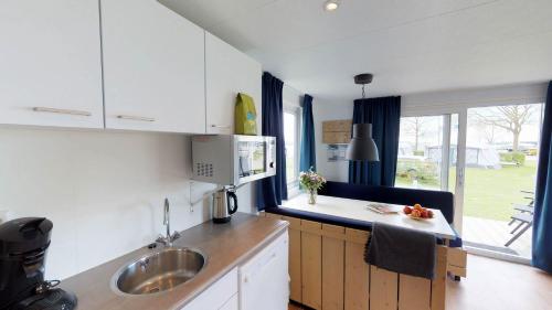 a kitchen with white cabinets and a sink at Villapark de Paardekreek in Kortgene