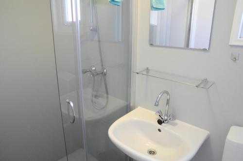a white bathroom with a sink and a shower at Villapark de Paardekreek in Kortgene