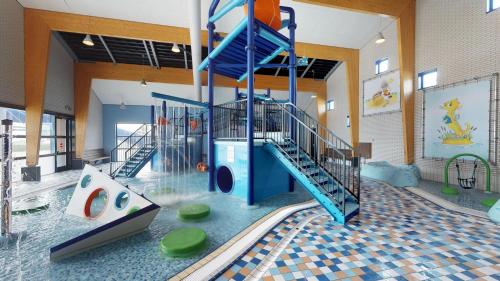 an indoor playground with a slide in a building at Villapark de Paardekreek in Kortgene