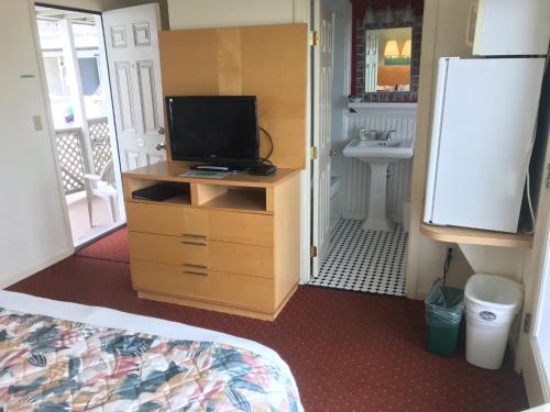 a bedroom with a television on a dresser with a sink at The Corsair & Cross Rip Oceanfront in Dennis Port