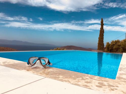 a pair of glasses sitting on the edge of a swimming pool at Luxus Tholos Bay in Thólos