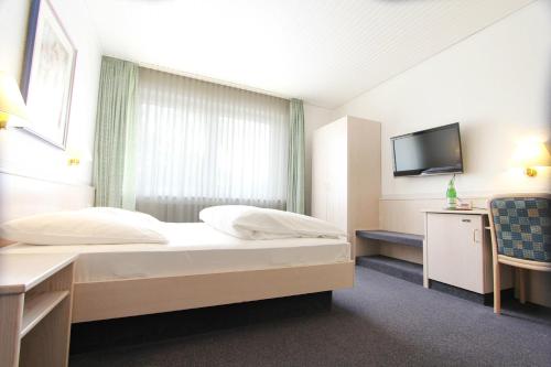 a hotel room with a bed and a tv at Landhaus Michels garni in Kaarst