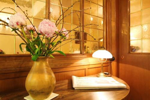 un vaso con fiori rosa su un tavolo accanto a una lampada di Landhaus Michels garni a Kaarst
