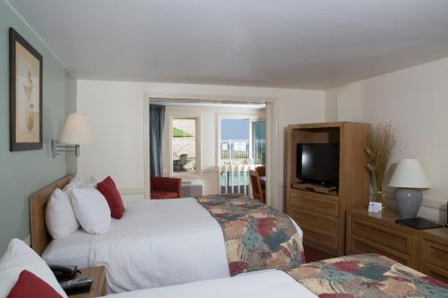 a hotel room with two beds and a television at The Corsair & Cross Rip Oceanfront in Dennis Port