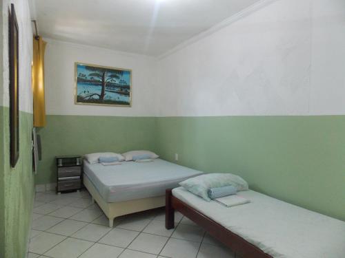 Duas camas num quarto com paredes verdes e brancas em Pousada Bom Jesus em Tamandaré