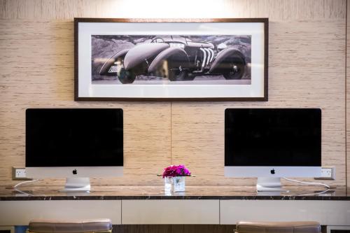 a desk with two monitors and a picture of a car at Palladio Hotel Buenos Aires - MGallery Collection in Buenos Aires