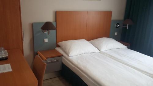 1 cama con almohadas blancas y cabecero de madera en Noclegi, Restauracja Eden en Witaszyce