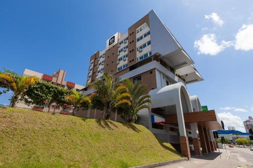 a building on a hill with palm trees in front of it at Tri Hotel Executive Criciúma in Criciúma