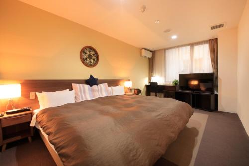 a bedroom with a large bed and a clock on the wall at Hotel Tohkai in Atsugi