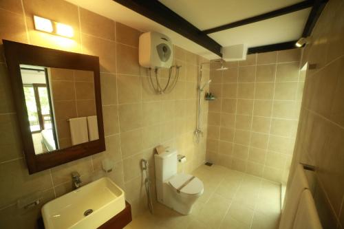 a bathroom with a toilet and a sink and a mirror at Sennya Resorts in Belihuloya