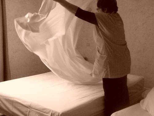 a woman standing on a bed in front of a mirror at Hostellerie d'Héloïse Logis in Cluny