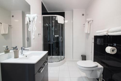 a bathroom with a toilet and a sink and a shower at Aparthotel Koroni Home in Raszyn