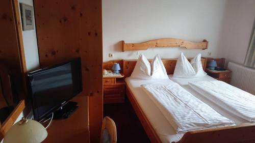 a bedroom with two beds and a flat screen tv at Hotel Alpenrose in Tauplitzalm