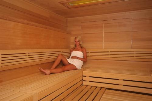 a woman is sitting in a sauna at Hotel Alpenrose in Tauplitzalm