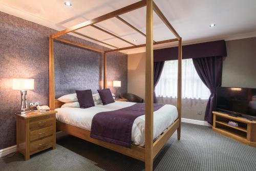 a bedroom with a canopy bed and a television at Widnes Halton Everglades Park Hotel in Widnes