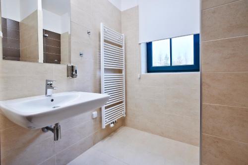 ein Bad mit einem weißen Waschbecken und einem Fenster in der Unterkunft Penzion Al Capone Mníšek in Mníšek pod Brdy
