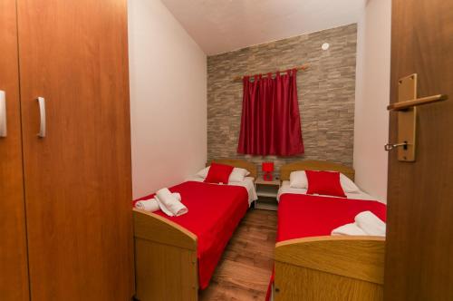 two beds in a small room with red sheets at Apartments Vukman in Trogir