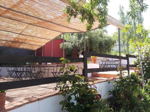 a patio with tables and chairs under a roof at Hotel Finca Aldabra in Pinos Genil