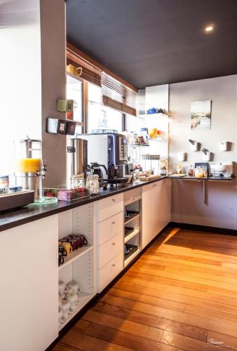 a large kitchen with white cabinets and a wooden floor at Hotel Des Lices in Rennes