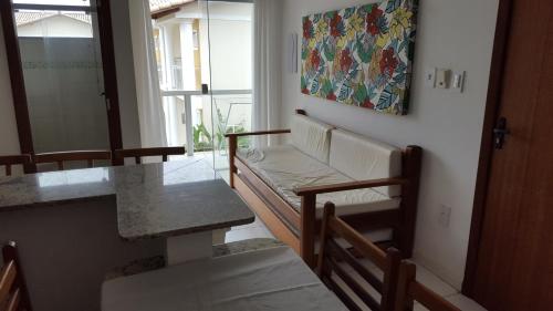 una habitación con un banco, una mesa y una pintura en Condomínio Mont Hebron - Apto 3A, en Porto Seguro