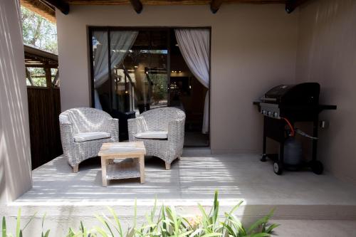 two wicker chairs and a piano on a porch at Maya Manor in Hoedspruit