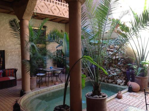 un patio con una piscina con plantas y una mesa en Riad Mehdia, en Marrakech