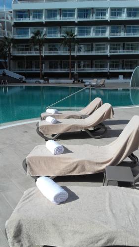 two lounge chairs and a swimming pool with a building at Gara Suites Golf & Spa in Playa de las Americas