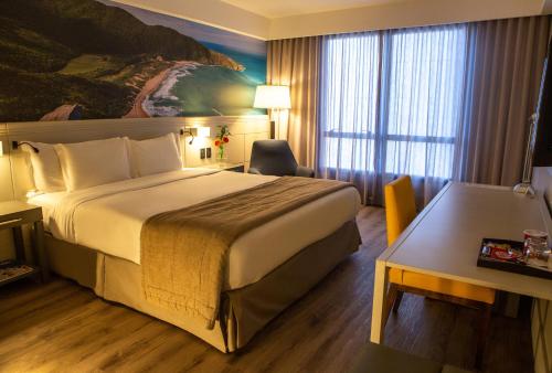 a hotel room with a bed and a desk at Novotel Florianopolis in Florianópolis