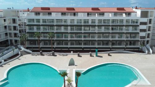 a large apartment building with two large swimming pools at Gara Suites Golf & Spa in Playa de las Americas