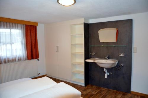 a bedroom with a bed and a sink and a window at Haus Tschiderer in Kappl
