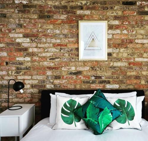 a bedroom with a brick wall and a bed with green pillows at N5 Townhouse, Brighton Sleeps 20 in Brighton & Hove