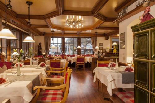 a restaurant with white tables and chairs and a chandelier at Flair Hotel Adlerbad in Bad Peterstal