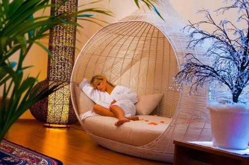 a woman is sitting in a wicker swing at Granpanorama Hotel StephansHof in Villandro