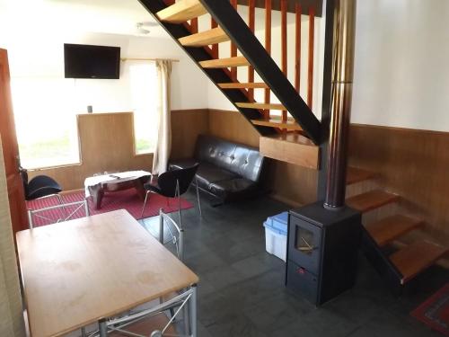 a living room with a staircase and a stove at Cabañas Bosque Sur in Puerto Varas