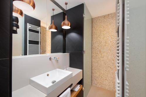 ein Badezimmer mit einem weißen Waschbecken und einem Spiegel in der Unterkunft Rogla – Hotel Rogla in Resnik