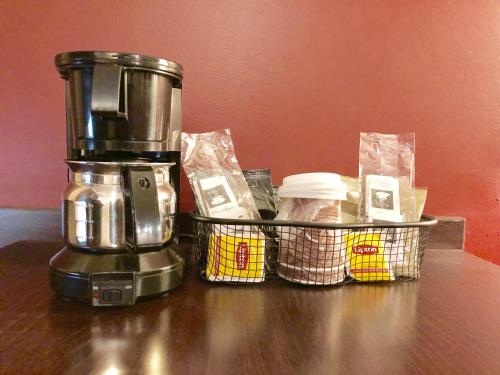 a coffee maker sitting on a table next to a basket at Regal Inn Chicago O'Hare - Franklin Park in Franklin Park