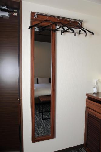 a mirror on a wall in a room with a bed at One's Hotel Fukuoka in Fukuoka