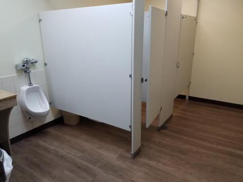 a bathroom with a urinal and a stall with a toilet at Baymont by Wyndham Grovetown Augusta in Augusta