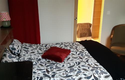a black and white bed with a red pillow on it at Maison Even in Dinan