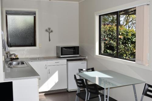 cocina con mesa, fregadero y ventana en Coastal Motor Lodge en Thames