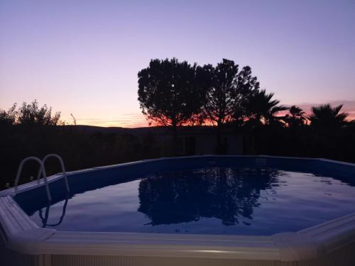 una piscina con puesta de sol en el fondo en Casita Movil Rural, en Cuesta de la Palma