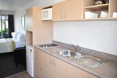 a kitchen with a sink and a bed in a room at Baywatch Motor Inn in Mount Maunganui