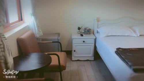 a bedroom with a bed and a table and a chair at Just Coffee Hostel 5 in Beigan