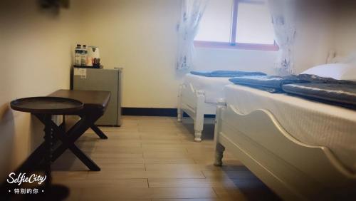 a room with two beds and a table and a window at Just Coffee Hostel 5 in Beigan