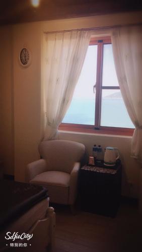a living room with a chair and a window at Just Coffee Hostel 5 in Beigan