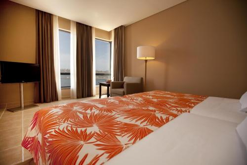 a hotel room with a bed and a large window at Pestana Tropico Ocean & City Hotel in Praia