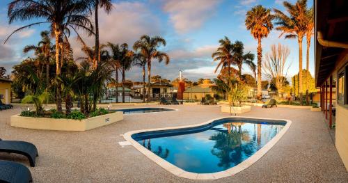a swimming pool in a courtyard with palm trees at BIG4 Whiters Holiday Village in Lakes Entrance